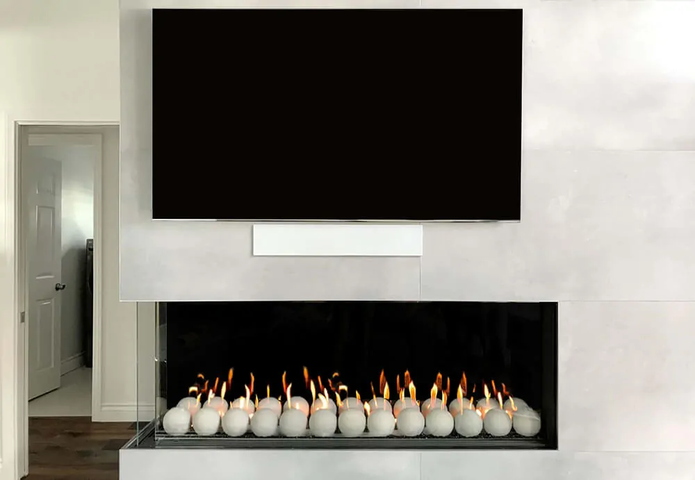 Modern linear Flare Left Corner 70" fireplace with decorative white spheres and a mounted TV above. LC-70