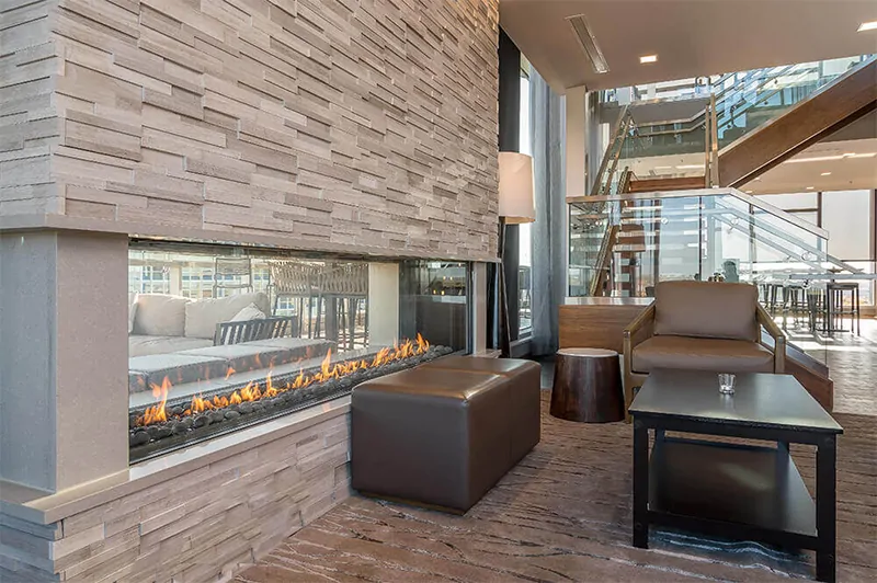 Modern living space with a double-sided linear See Through 100" Indoor/Outdoor Flare Fireplace and contemporary furnishings.