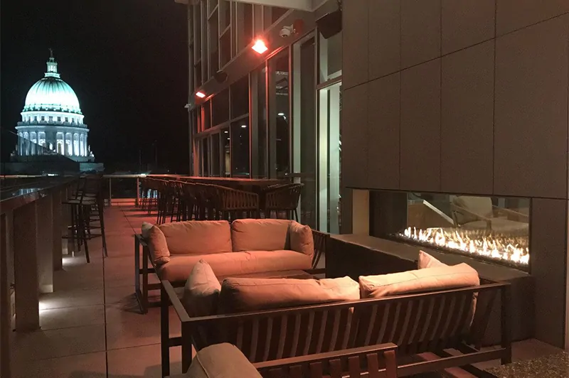 Outdoor patio with a modern linear See Through 100" fireplace and a view of a lit capitol building at night.