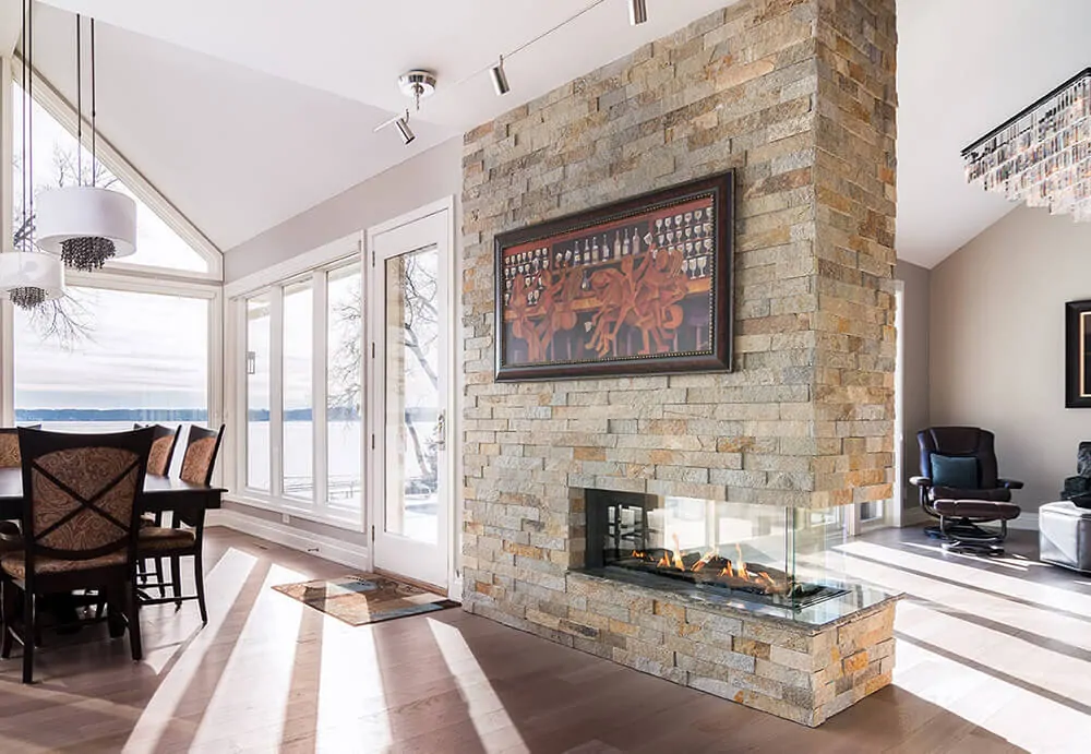 Three sided gas fireplace in an open-plan living and dining space: Flare Room Definer with brick surround and large windows.