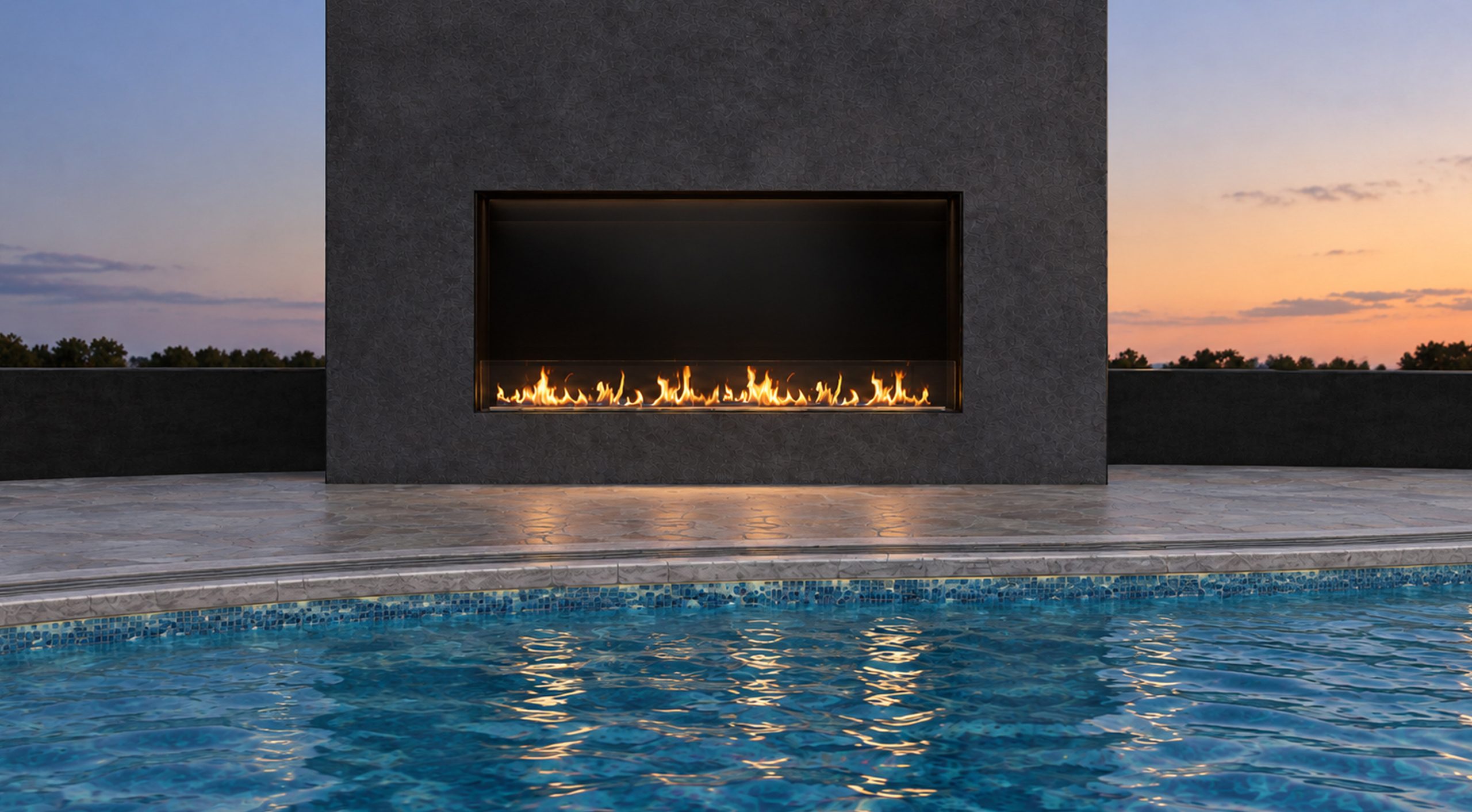 Front view of the VFF50H linear fireplace in a charcoal wall beside a curved swimming pool at dusk.