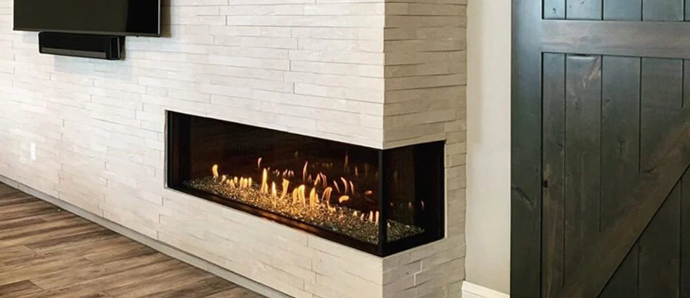 Flare Right Corner 70-inch linear gas fireplace visible from two sides of an open-plan living room with a stacked-stone surround