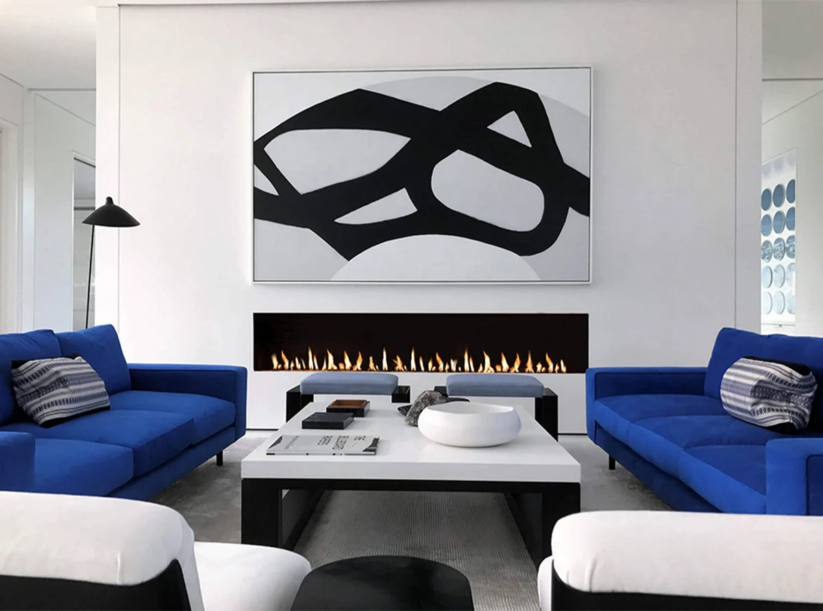 Modern Linear Flare Front Facing 100" Fireplace in a contemporary living room with bold blue sofas and black-and-white abstract artwork.