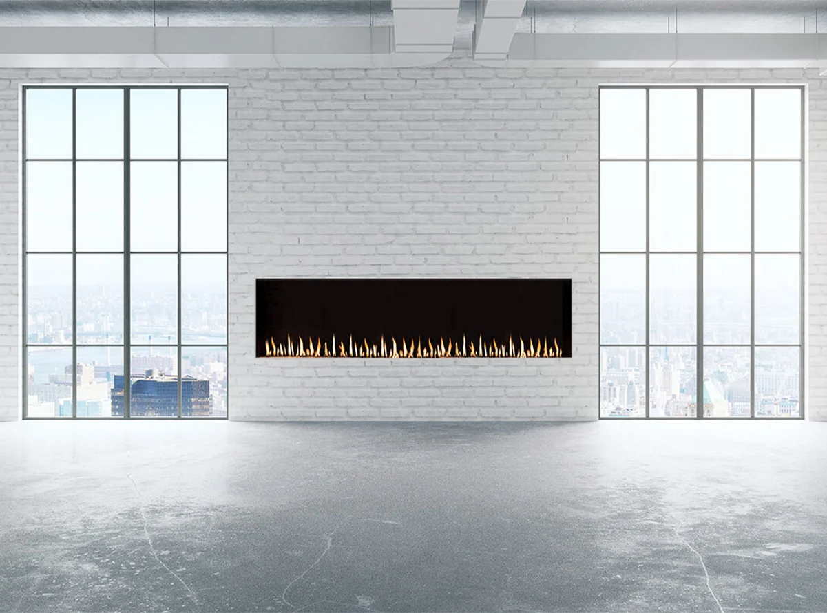 Modern linear Flare Front Facing 80" fireplace set in a white brick wall with large industrial-style windows and a panoramic city view. FLARE-FF-80-EH