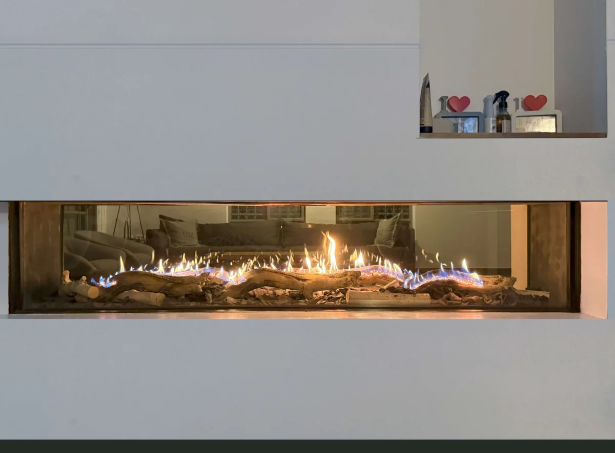 Flare See-Through 80 double-sided gas fireplace with the Summit Burner and cool-touch double glass, showing driftwood log media and a full flame